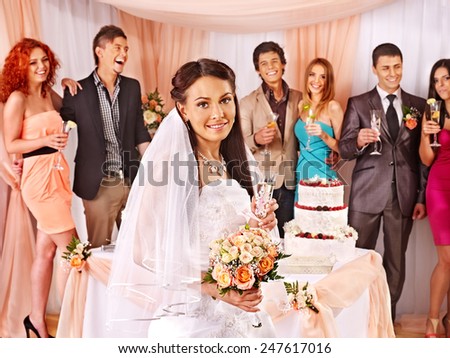 Group people at wedding table with cake. Bride with a bouquet of flowers in the foreground