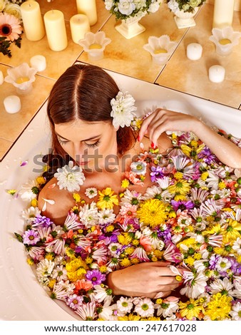 Woman relaxing at water spa. Girl takes a bath with flowers