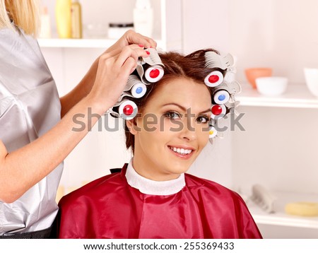 Happy woman wear hair curlers on head. Barber is in  barbershop