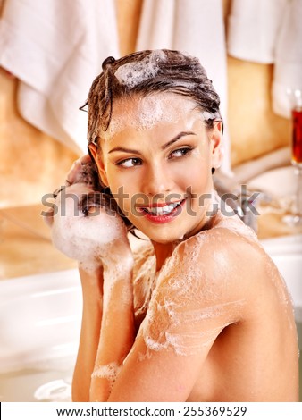 Woman relaxing at water in bubble bath. Girl looking to side.