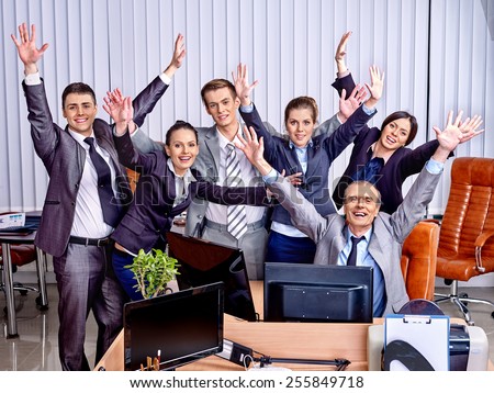 Happy group business people with hand up in office. Venetian blinds background.