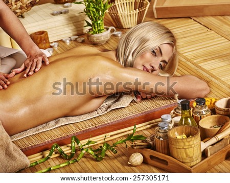 Blond woman getting massage in tropical spa.Bamboo floor.