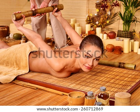 Woman getting bamboo luxury massage. Wooden bed.