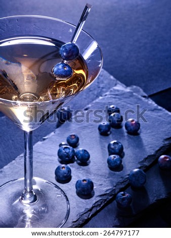Blueberry gold drink on black background. Berries scattered
