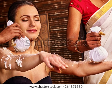 Woman having ayurvedic massage with pouch of rice. Hands outstretched