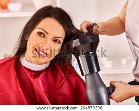 Woman at hairdresser. Styling with a hair dryer. Barber  is in hair salon with a client