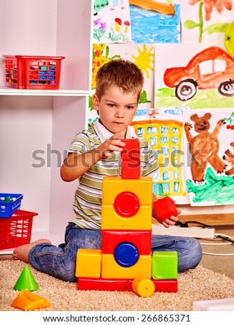 Little boy  in kindergarten stacking block. Painting  background.