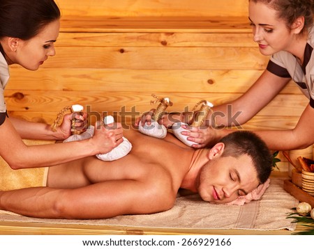 Man getting herbal ball massage treatments  in spa. Two women.