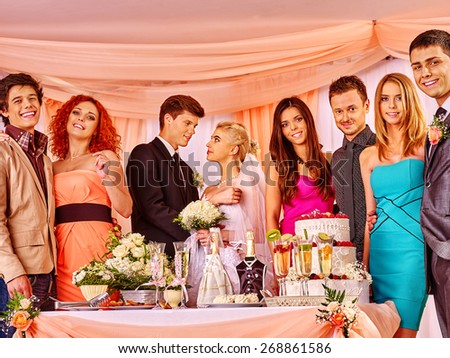 Group people at wedding table with cake. In the center of bride and groom