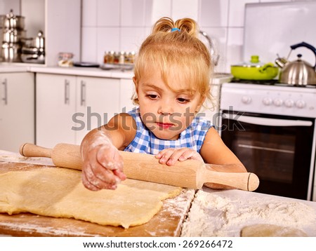 Child with rolling-pin dough at kitchen.