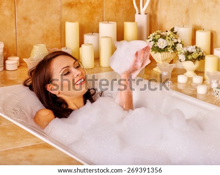 Woman relaxing at water in bubble bath.