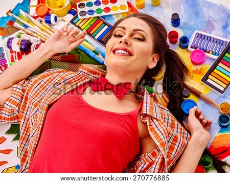 Artist woman lying on paint palette. Red t-shirt.