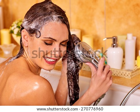 Woman washes her head at home bathroom. Wetting hair.