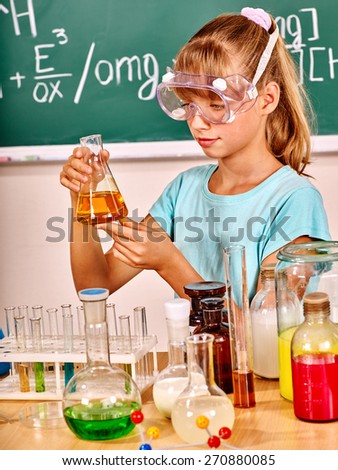 Child holding flask in chemistry class. Mask on face.