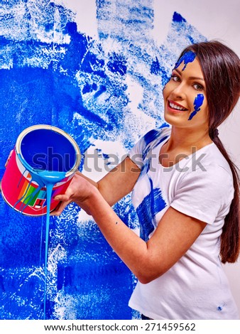 Happy woman paint wall at home. Pouring liquid.