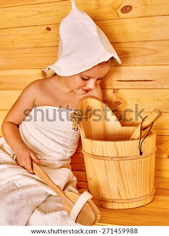 Happy child relaxing at sauna. Wooden bucket