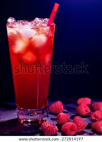 Red raspberry drink  with ice cube and straw on black background.