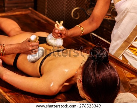 Woman having ayurvedic massage with pouch of rice. Girl lying face down.