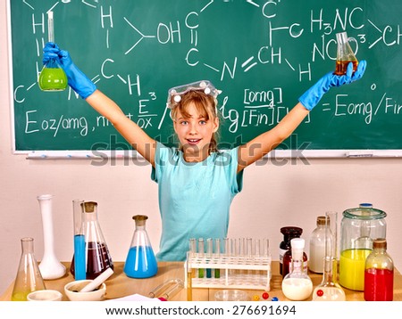 Child holding flask in chemistry class. Green blackboard background.