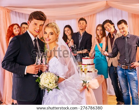 Happy wedding couple drinking champagne. Gosts background.