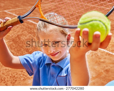 Child girl with racket and ball on  tennis court.