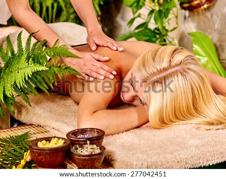 Woman getting back massage in tropical spa.Hands on shoulders