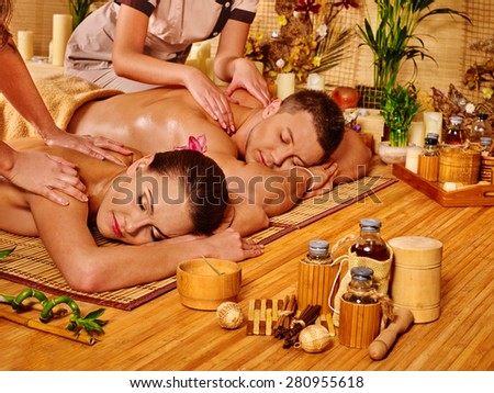 Man and woman relaxing in bamboo spa getting massage.
