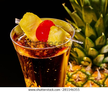 Champagne cocktail with cherry and whole pineapple with leaves . Top view