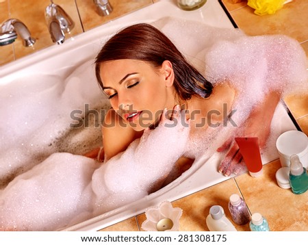 Beautiful woman with long hair relaxing at water in bubble bath.