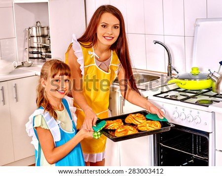 Mother and daughter bake cookies at home kitchen.