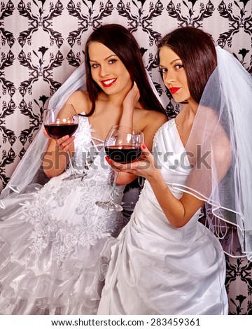 Wedding lesbians girl in bridal dress drinking red wine. Wallpaper background.