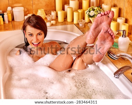 Woman relaxing at water in bubble bath. Visible bare feet.