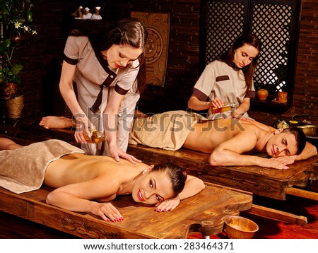 Couple  having oil Ayurveda spa treatment. Two masseuses are making massage.