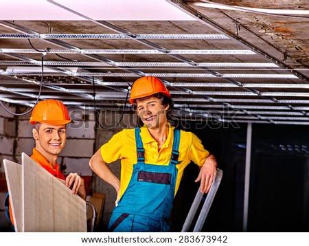 Men in builder uniform installing suspended ceiling