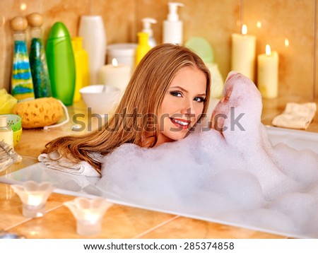 Happy smiling woman  taking bath with a lot of foam.