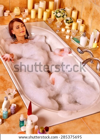 Woman relaxing at water in bubble bath. Top view.