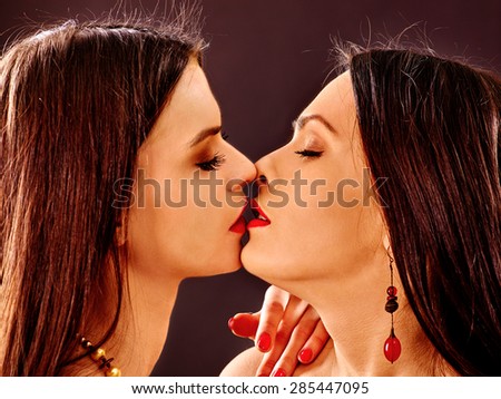 Portrait of  kissing lesbian women kissing .Grey background.