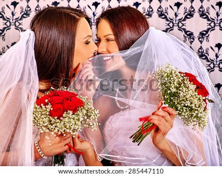 Wedding lesbians girl in bridal dress kissing. Wallpaper in background