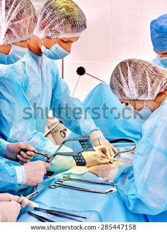 Sick patient and group doctors on gurney in operating room.