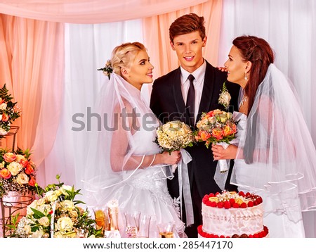 Happy wedding man and two bride holding flower bouquet. Group people.