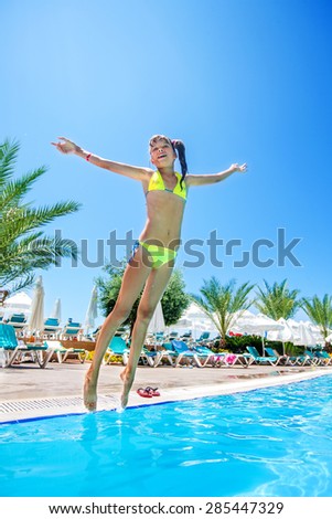 Little girl  in yellow bikini jump in swimming  pool.