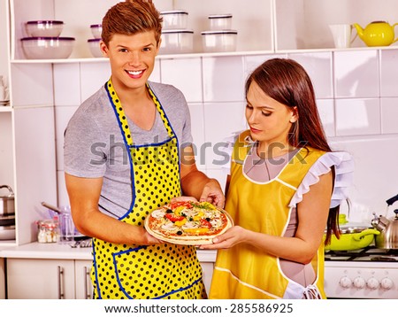 Young happy family cooking pizza at kitchen. Woman looking man.