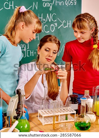 Teacher with children holding flask in chemistry class.