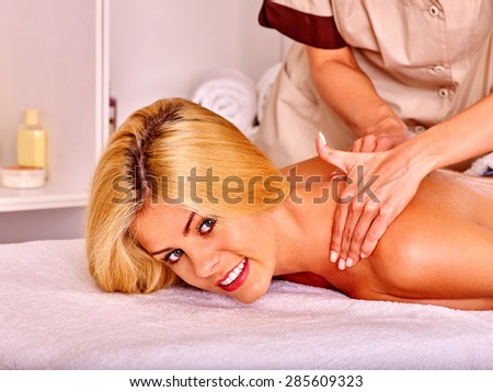 Blond woman getting massage in health resort and looking at camera .