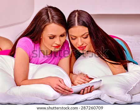 Two  Lesbian women see pictures in bed at tablet pc.