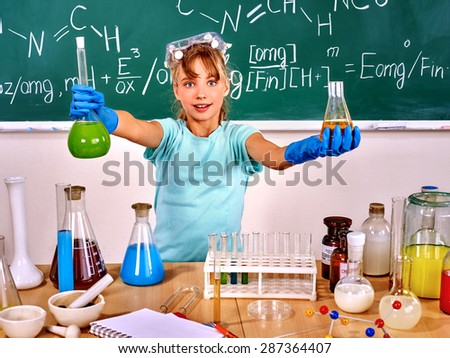 Child chemistry into mask holding flask in school.