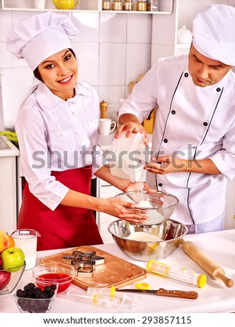 Two people  woman and man in chef hat cooking dough .