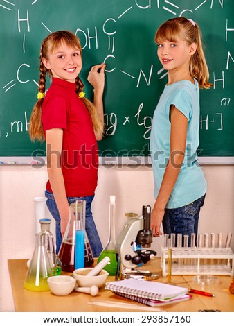 Happy child writing on blackboard  in chemistry class.