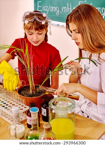 Child and teacher with pot plant  in biology class.