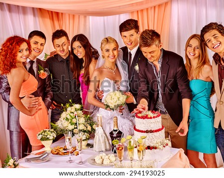 Group people at wedding table with cake. Groom and bride.